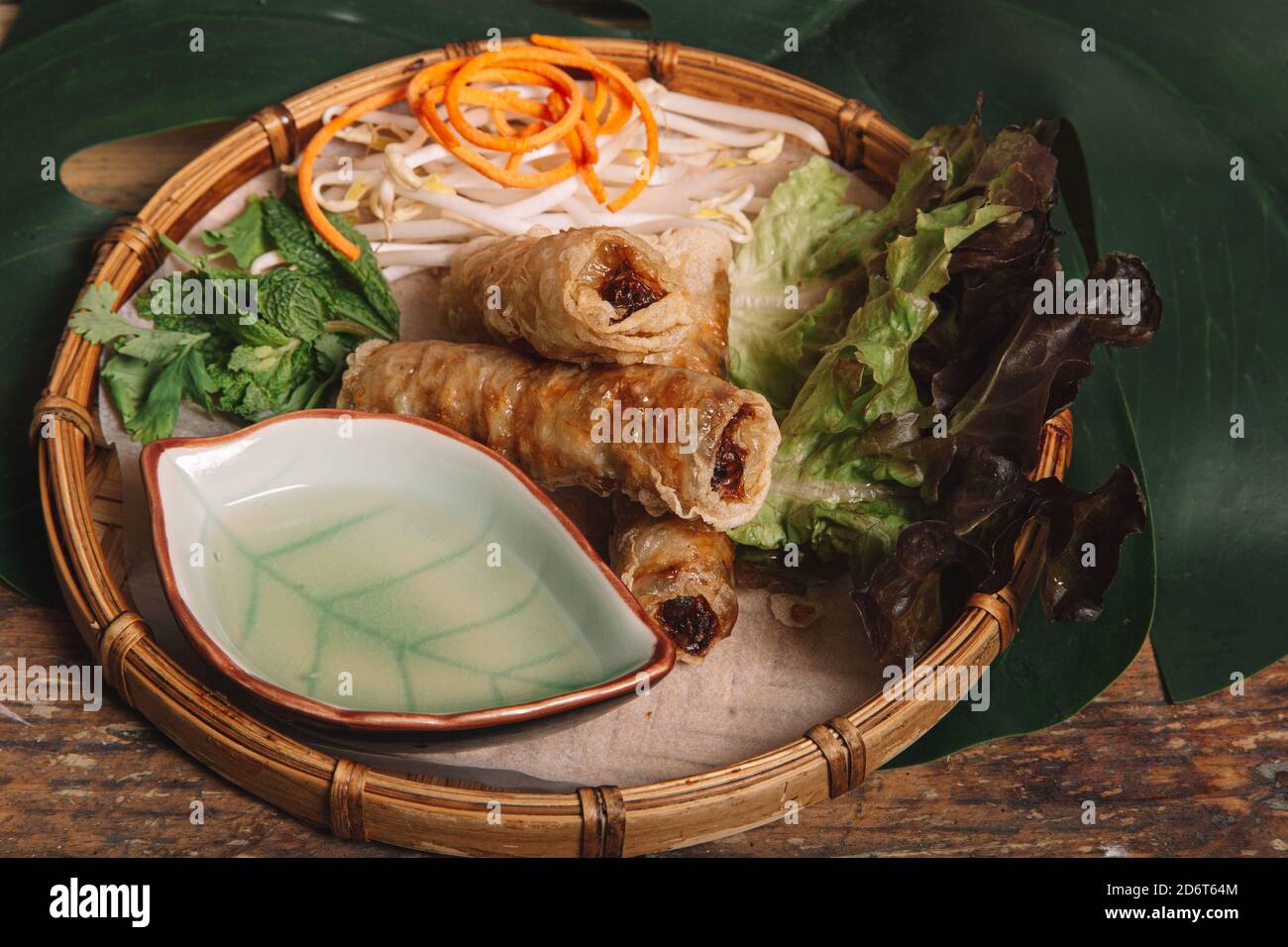 Grand angle de petits pains frits servis sur l'assiette avec Laitue fraîche et pousses de haricots sur table en bois en vietnamien restaurant Banque D'Images