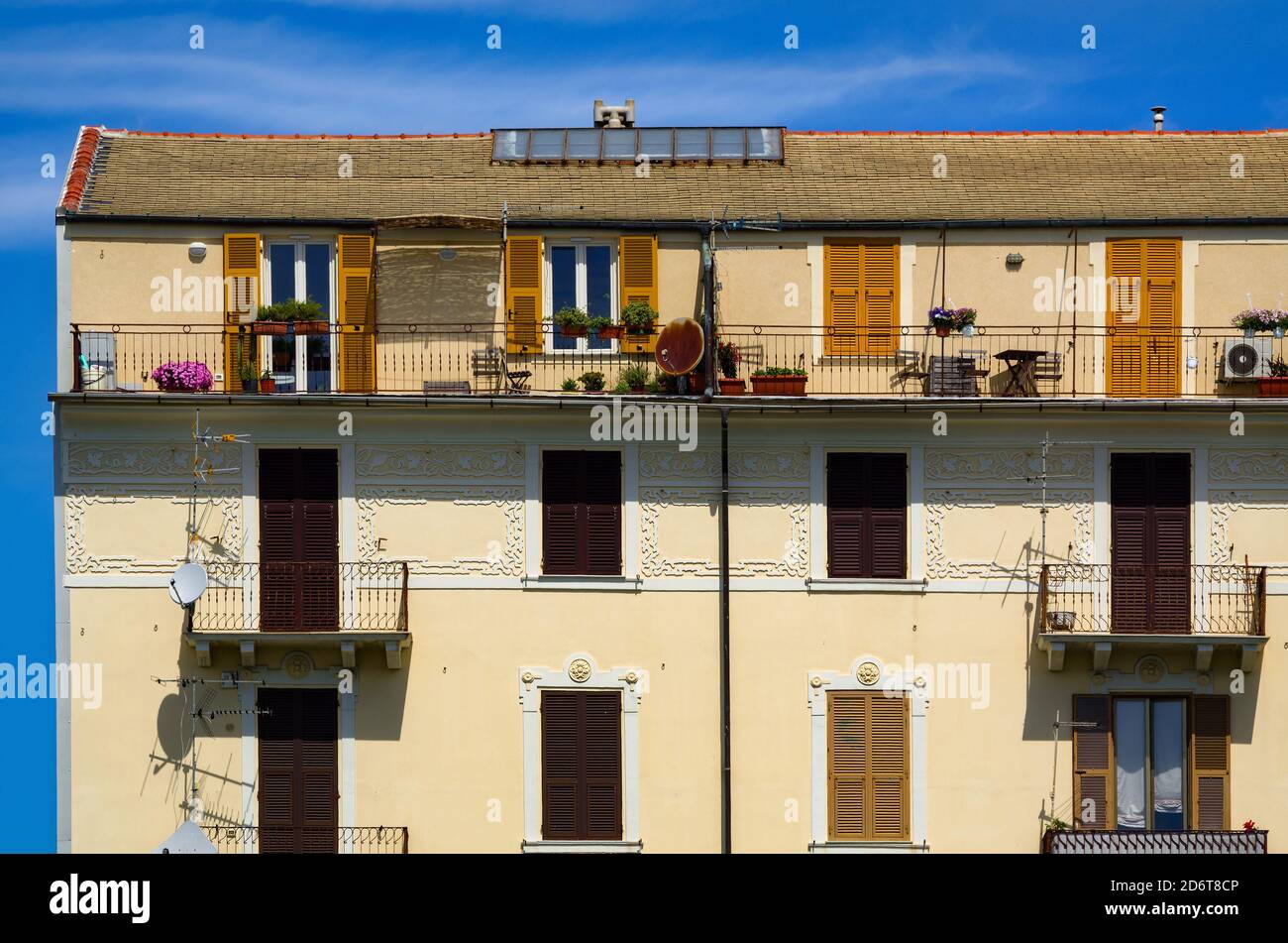 Façade d'un immeuble à Savona, Italie. Bâtiment jaune avec rangées de fenêtres et balcons. Banque D'Images