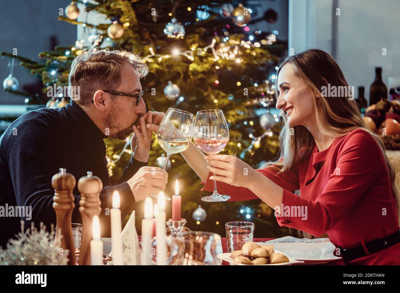 Un couple d'âge moyen boit du vin la veille de Noël Banque D'Images