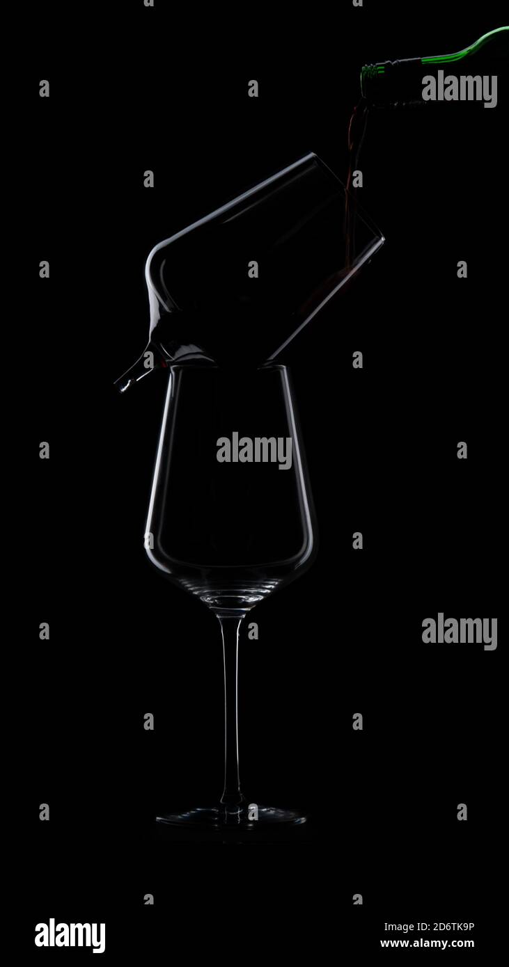 Le vin est versé dans une silhouette de verre sur fond noir. Un verre est cassé. Photo de haute qualité Banque D'Images