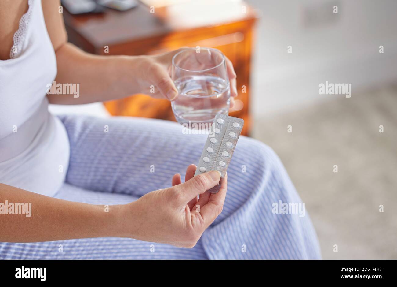Gros plan d'une femme d'âge mûr assise sur un pyjama portant un lit Prendre des médicaments Banque D'Images