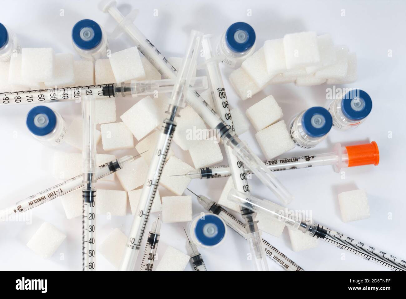 Dépendance au sucre, résistance à l'insuline, régime alimentaire malsain, pyramide des cubes de sucre, bouteilles d'insuline et seringue pour la vaccination sur fond blanc, diabète Banque D'Images
