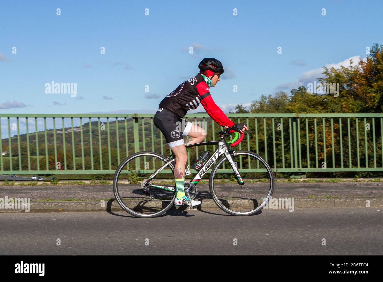 Cycliste mâle sur planète x fibre de carbone léger sport sur route vélo sur la route de campagne traversant le pont d'autoroute dans la campagne Lancashire, Royaume-Uni Banque D'Images