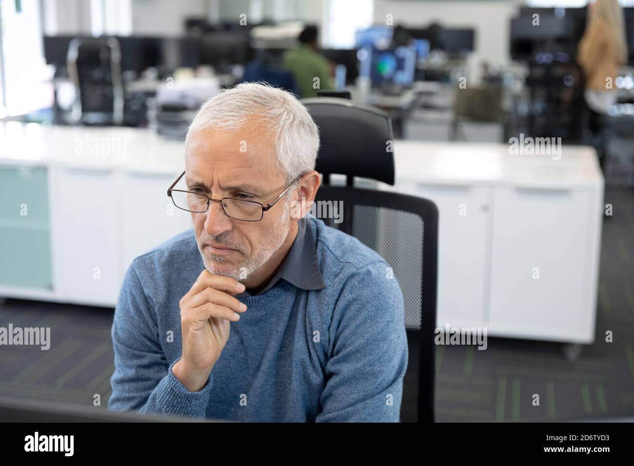 Homme d'affaires senior attentionné assis sur son bureau moderne Banque D'Images