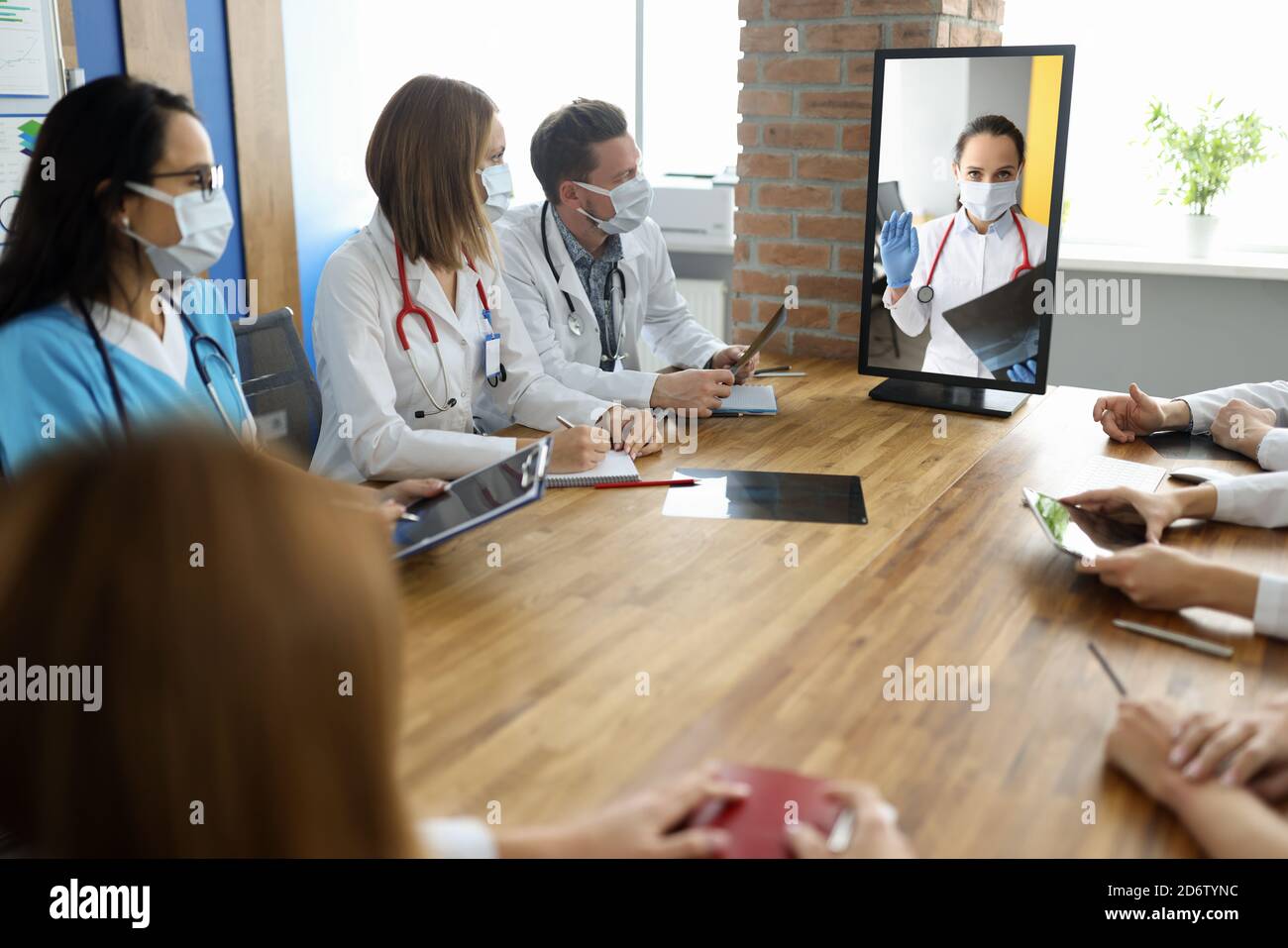 Le personnel médical s'assoit à la table avec les documents et regarde le moniteur sur lequel le médecin voit la conversation. Banque D'Images