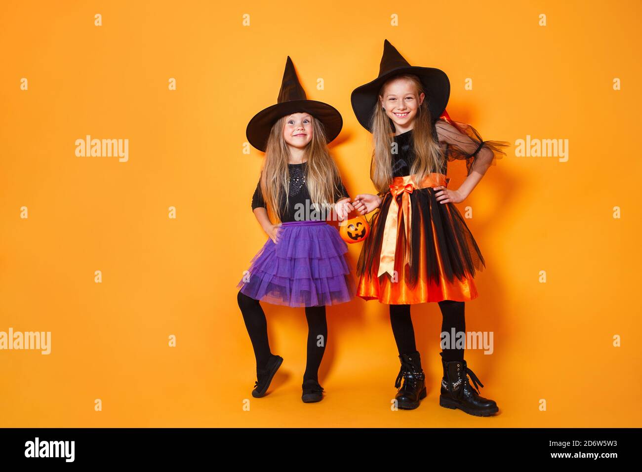 Joyeux enfant filles dans des costumes de sorcière sur fond orange Banque D'Images