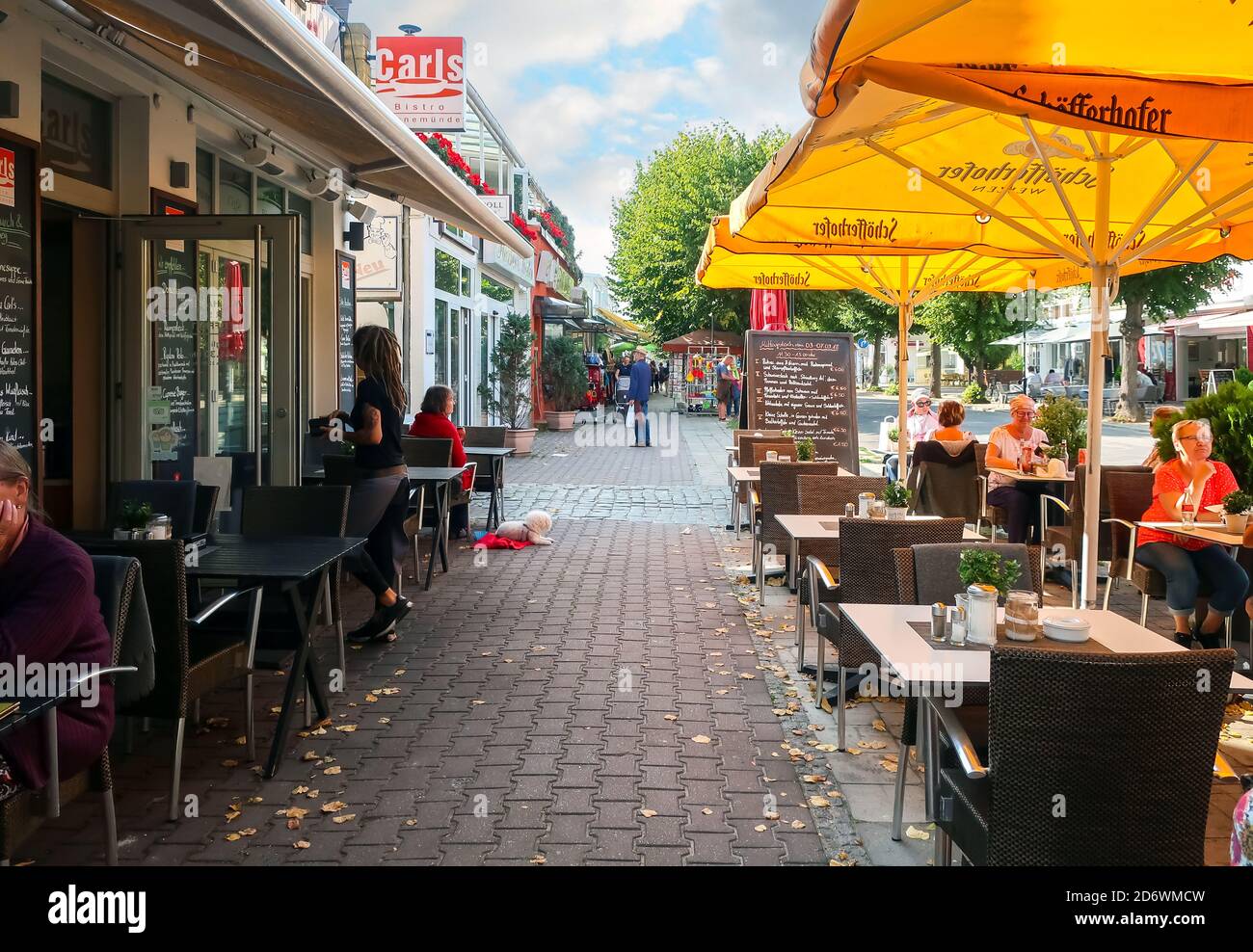 Les clients y compris un petit chien apprécient un café-terrasse dans le centre touristique de Warnemunde, en Allemagne Banque D'Images