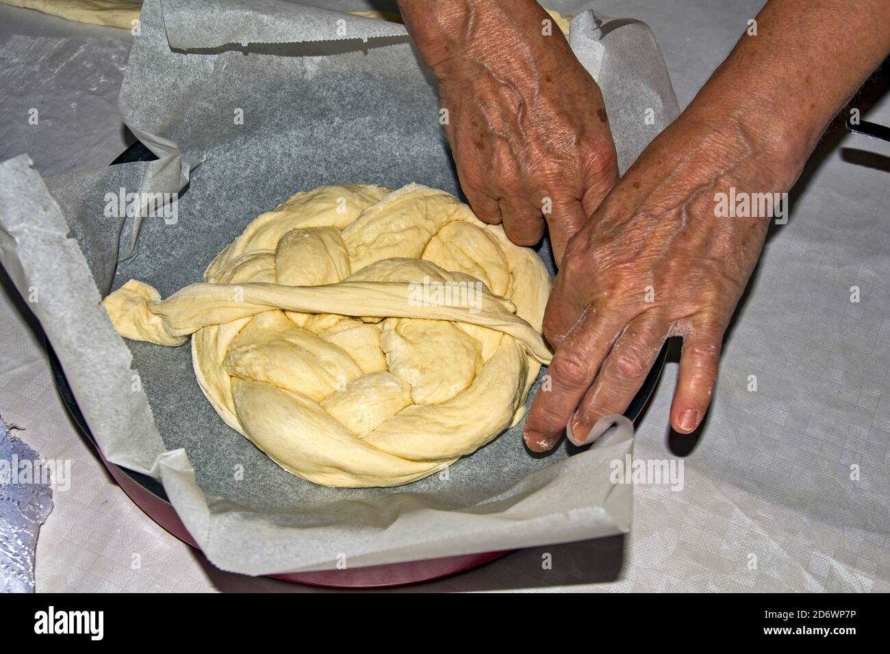 Les mains d'une femme au foyer âgée qui s'agenouillent un gâteau de fête - du pain pour les célébrations à venir. Le pain est ensuite cuit au four. Banque D'Images