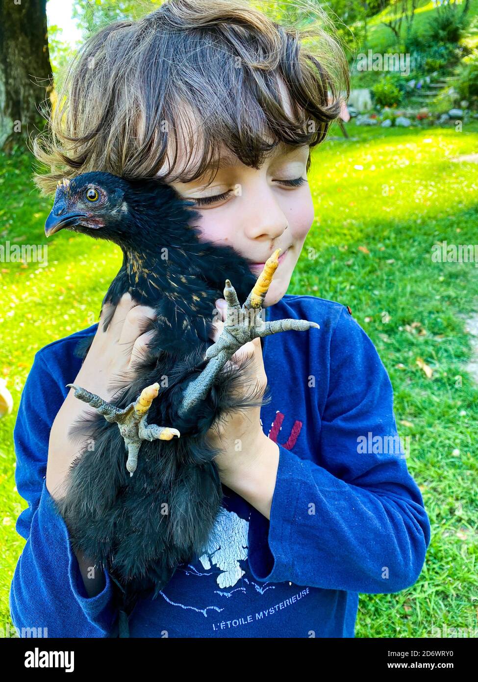 Enfant portant une poule dans ses bras. Banque D'Images
