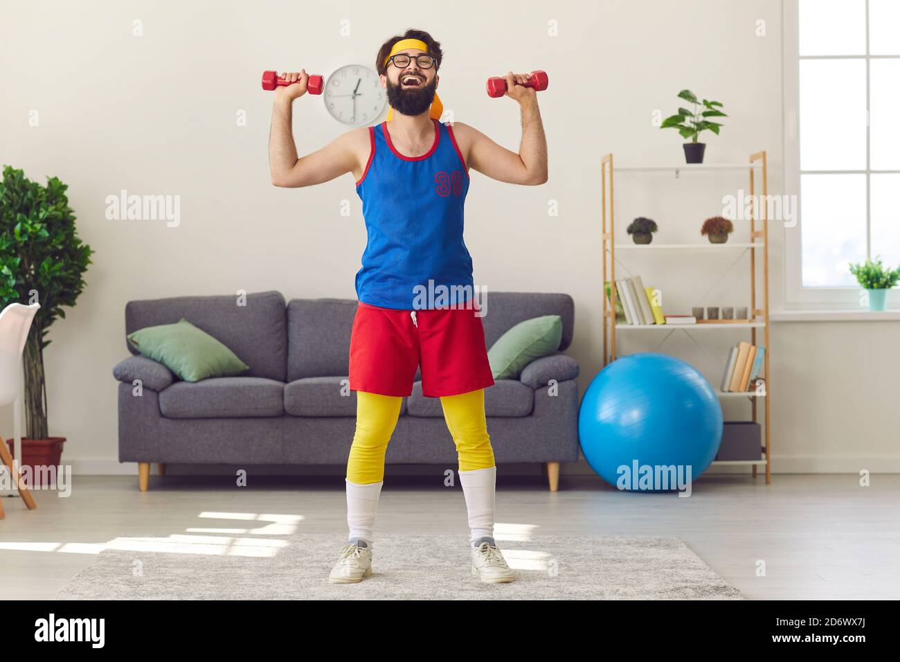 Drôle gai barbu homme faisant des entraînements sportifs avec des haltères à la maison dans le salon. Banque D'Images