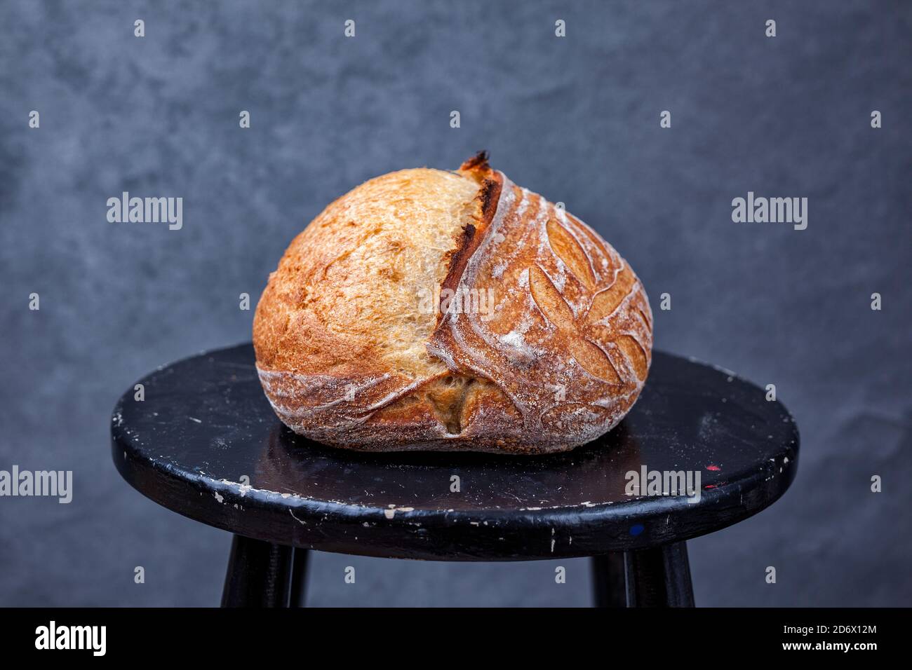 Pain artisanal de pain de pâte au levain maison traditionnel avec croûte sur un tabouret noir Banque D'Images