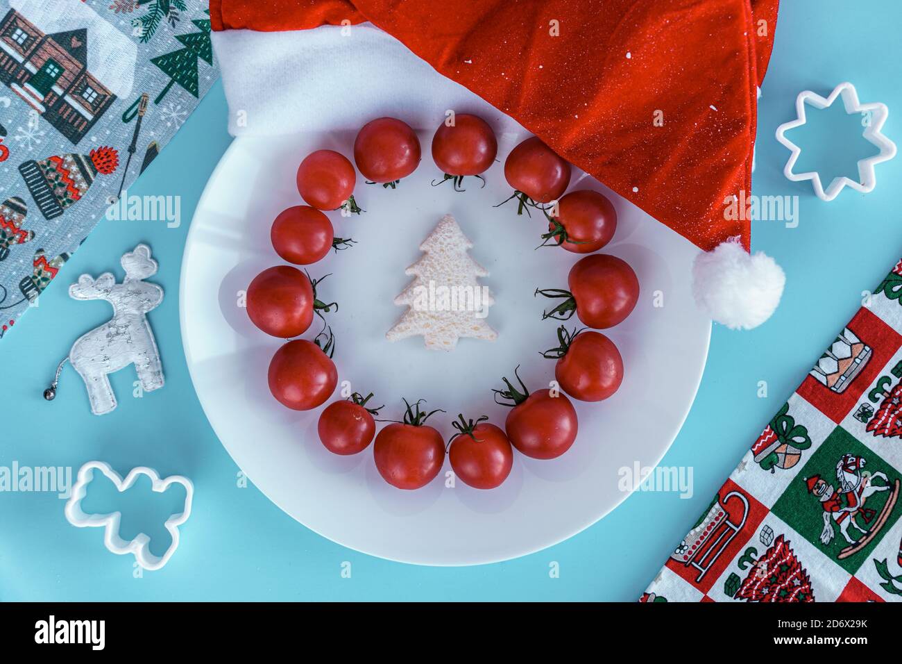 Noël, hiver, nouveau concept de l'année - mise en page plaque blanche sur laquelle il y a un arbre de Noël sculpté dans le pain et entouré de tomates cerises rouges avec le père noël Banque D'Images