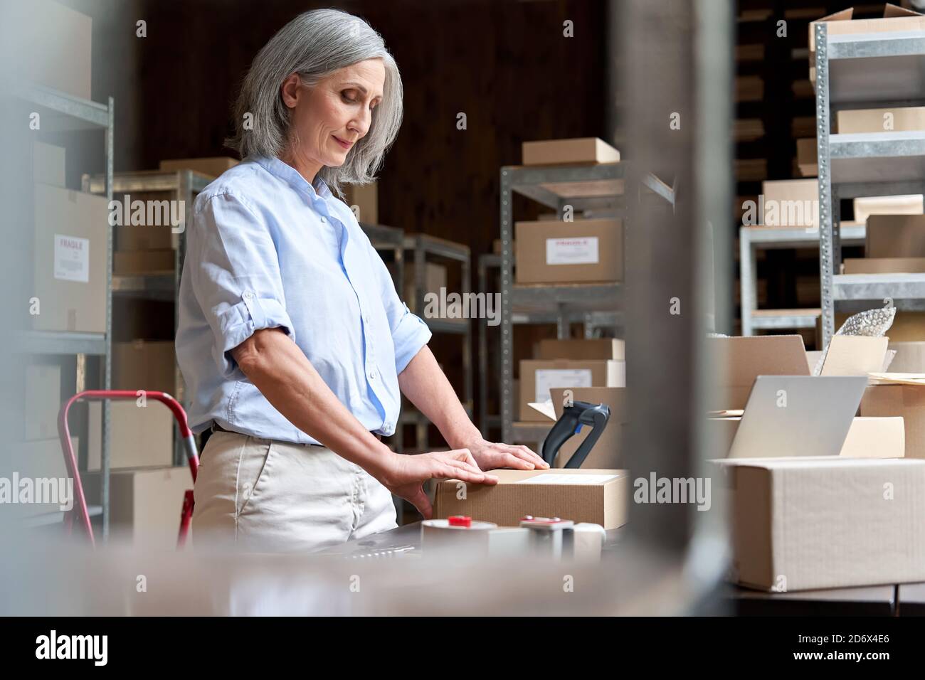 Mature femme en ligne magasin propriétaire d'affaires emballage colis boîte d'expédition. Banque D'Images