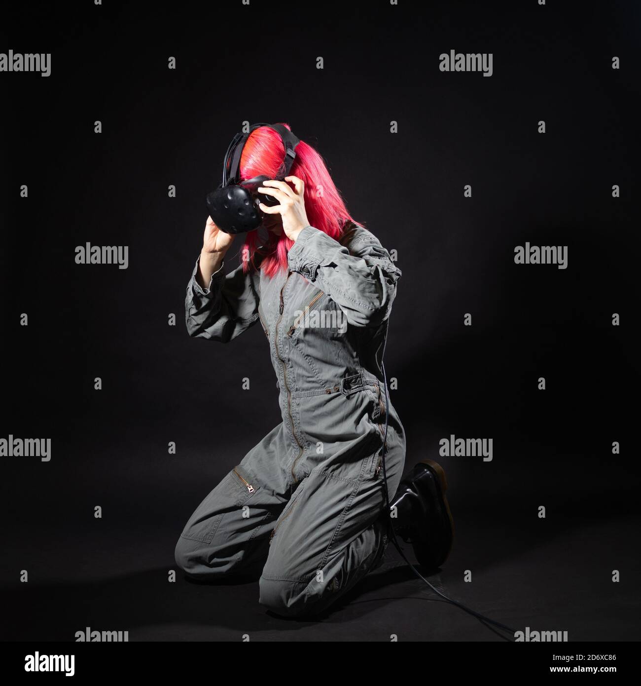 Réalité virtuelle et futurisme. Cyberpunk concept, un joueur aux cheveux roses. Jeune femme en combinaison et lunettes de réalité virtuelle, est dans une simulation. Banque D'Images
