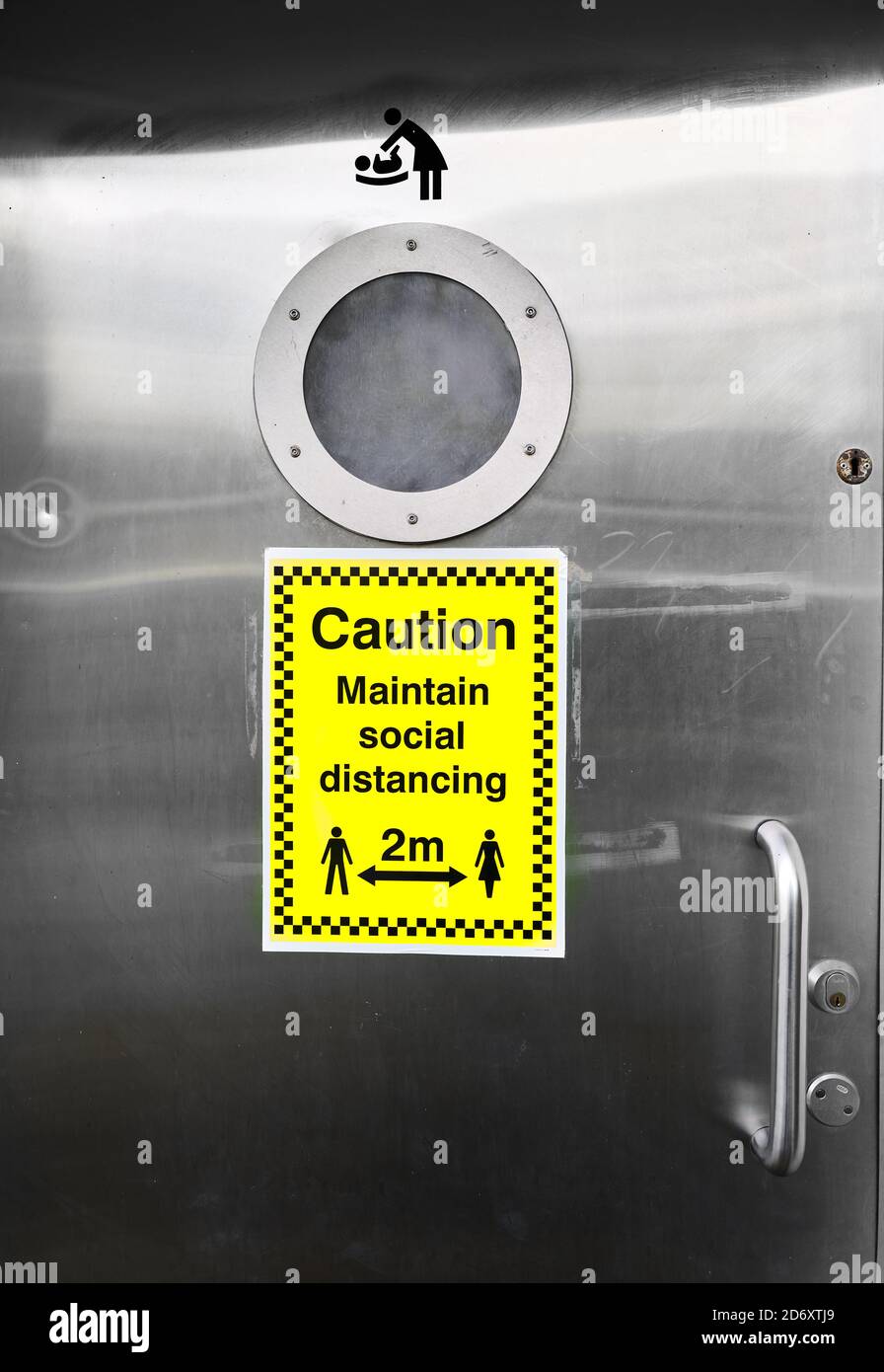 Avis sur une porte de toilettes publiques sur la prévention de la sread de Covid-19. Banque D'Images
