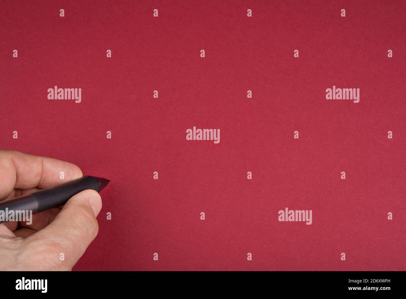 Main et stylo sur fond rouge vierge Banque D'Images