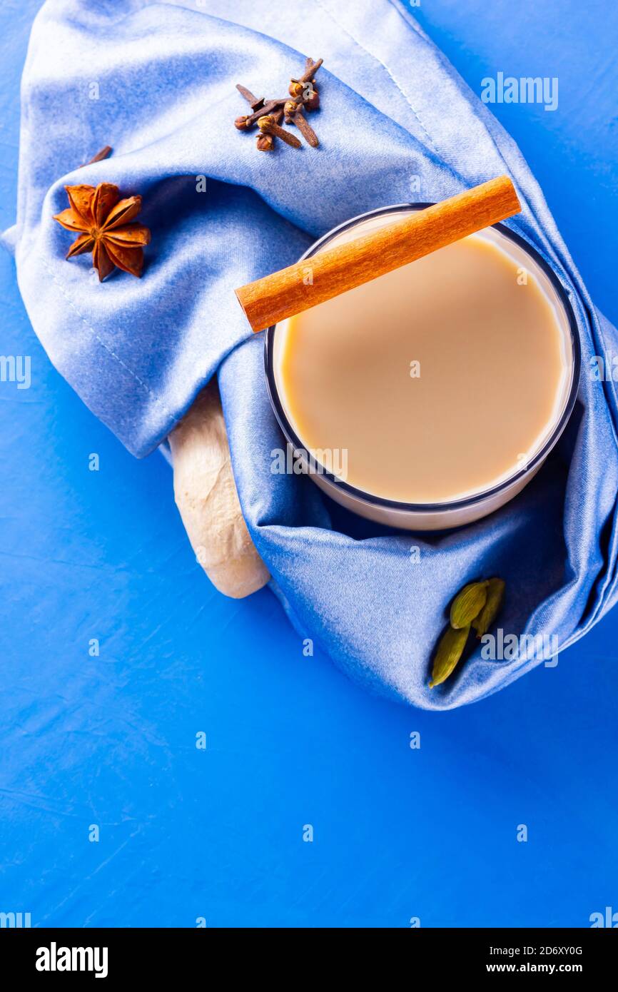 Thé au chaï masala sur une serviette bleue. Boisson traditionnelle indienne - thé masala avec diverses épices. Verre de thé masala sur fond bleu. Copier l'espace Banque D'Images