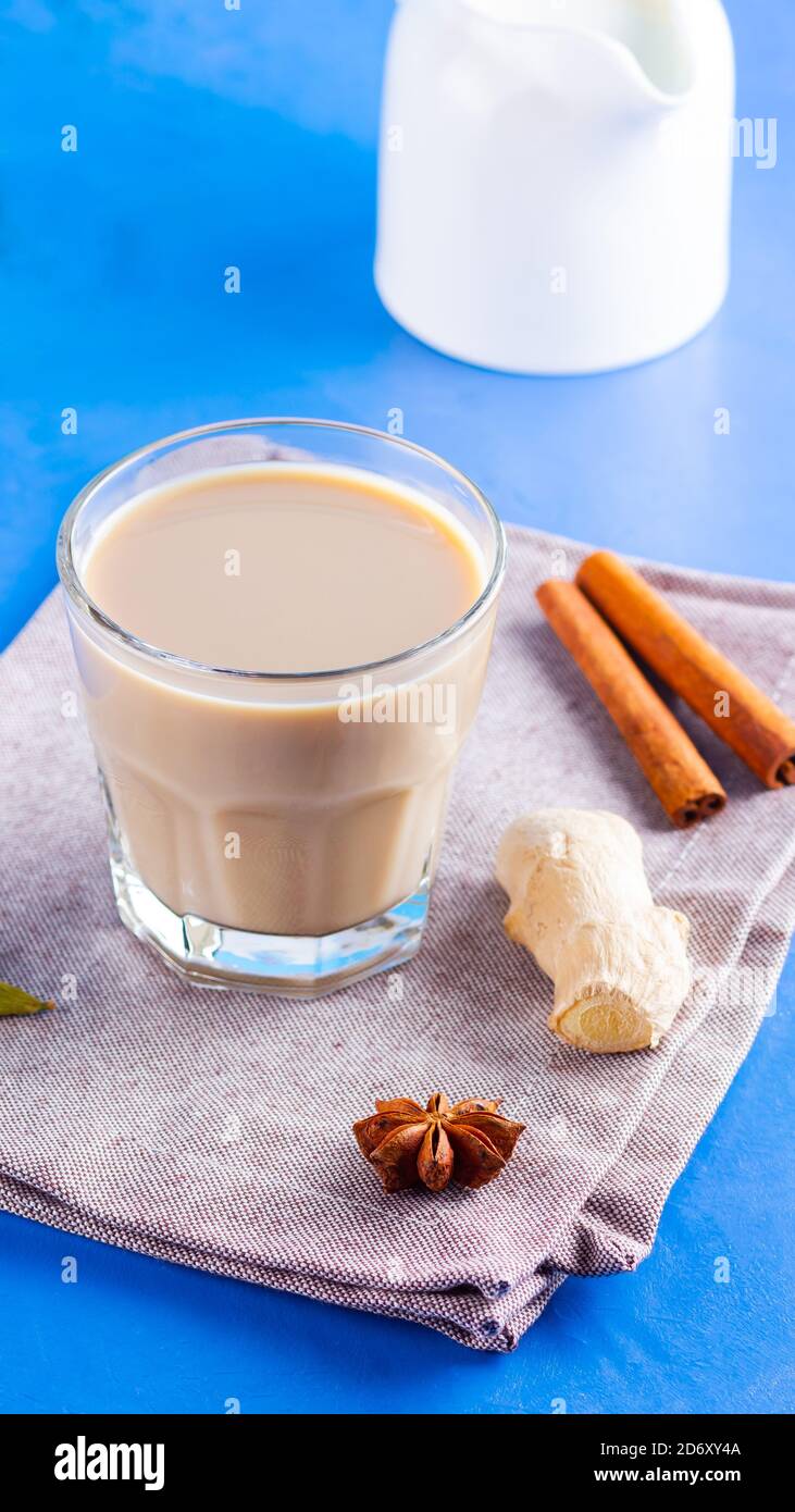 Thé au chaï masala sur une serviette en lin. Boisson traditionnelle indienne - thé masala avec diverses épices. Verre de thé masala sur fond bleu Banque D'Images