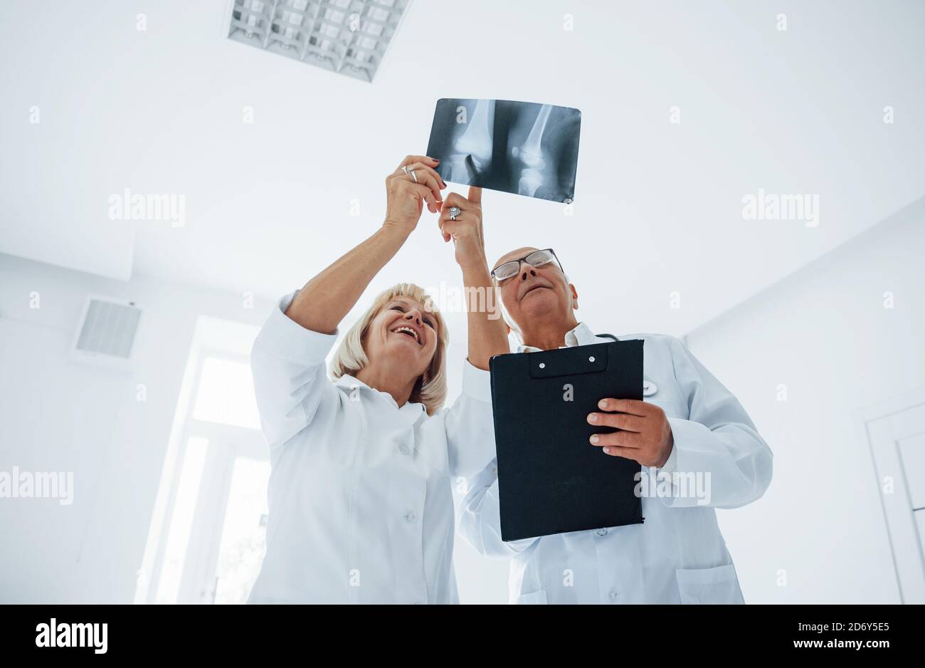 Homme et femme âgés médecins en uniforme blanc examine la radiographie des jambes humaines Banque D'Images