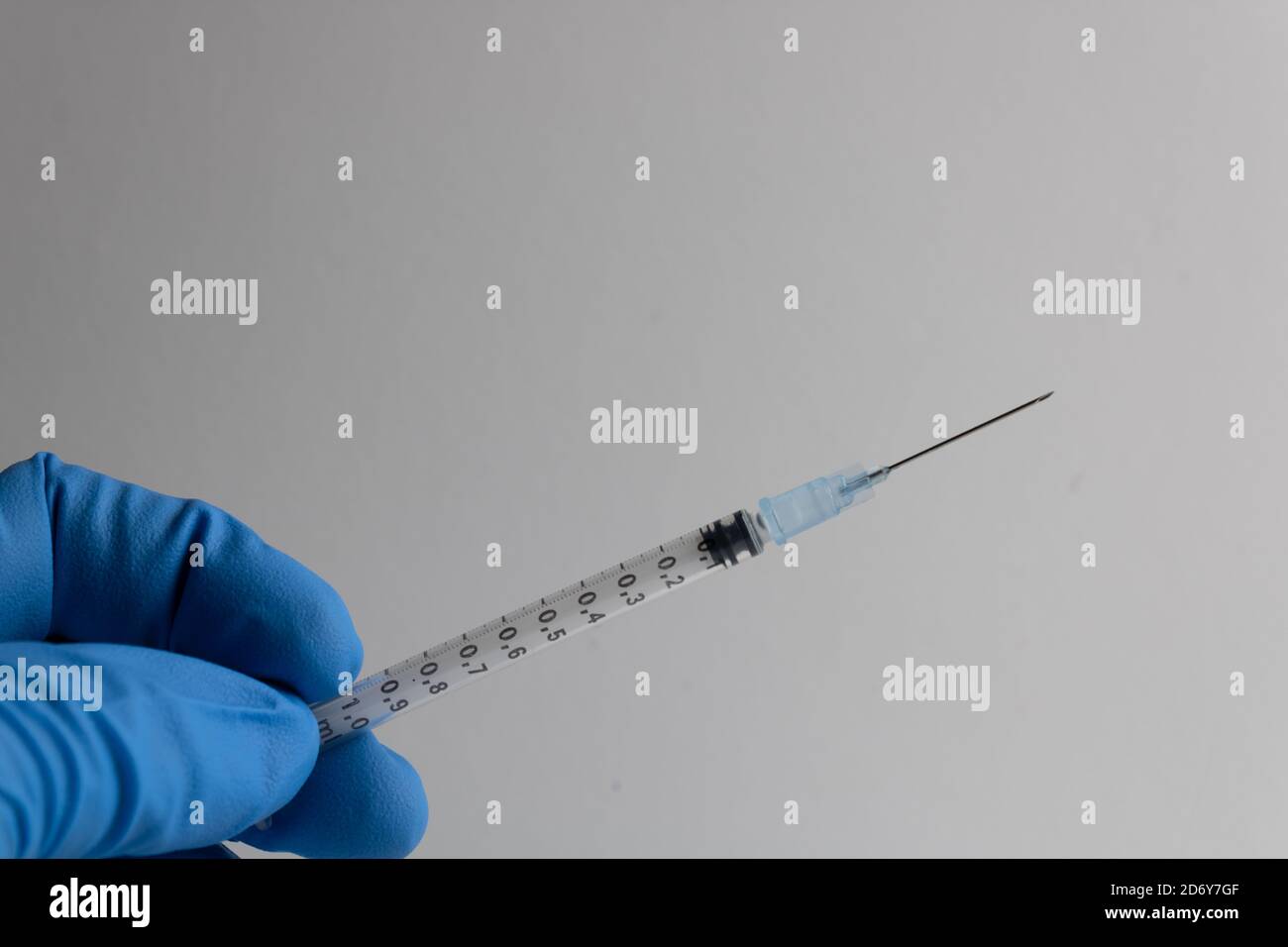seringue à aiguille maintenue par une infirmière avec une isolation bleue gant sur fond blanc Banque D'Images