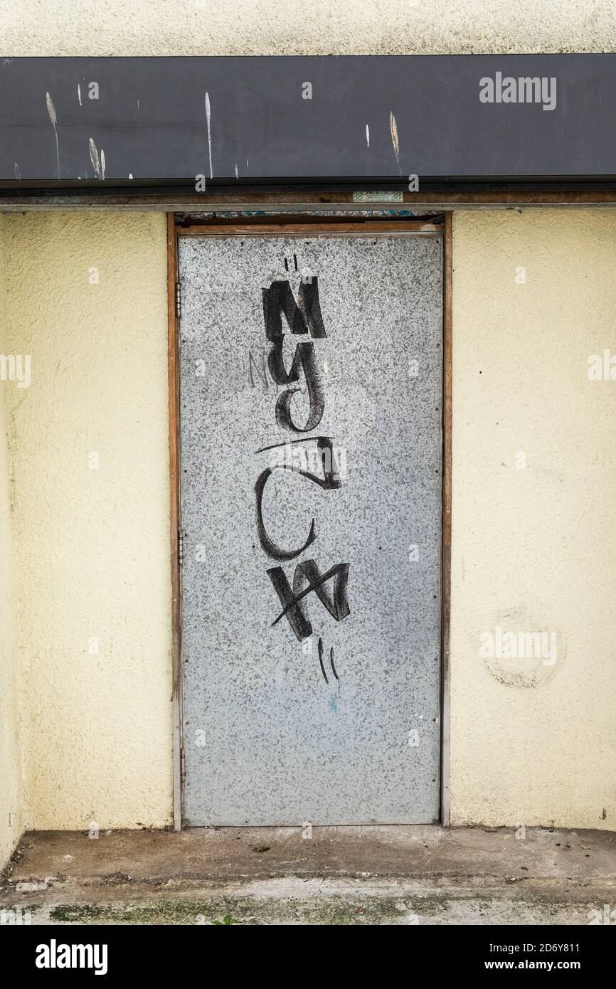 Graffiti laid sur une porte extérieure en métal dans un bâtiment du centre-ville de Newquay, dans les Cornouailles. Banque D'Images