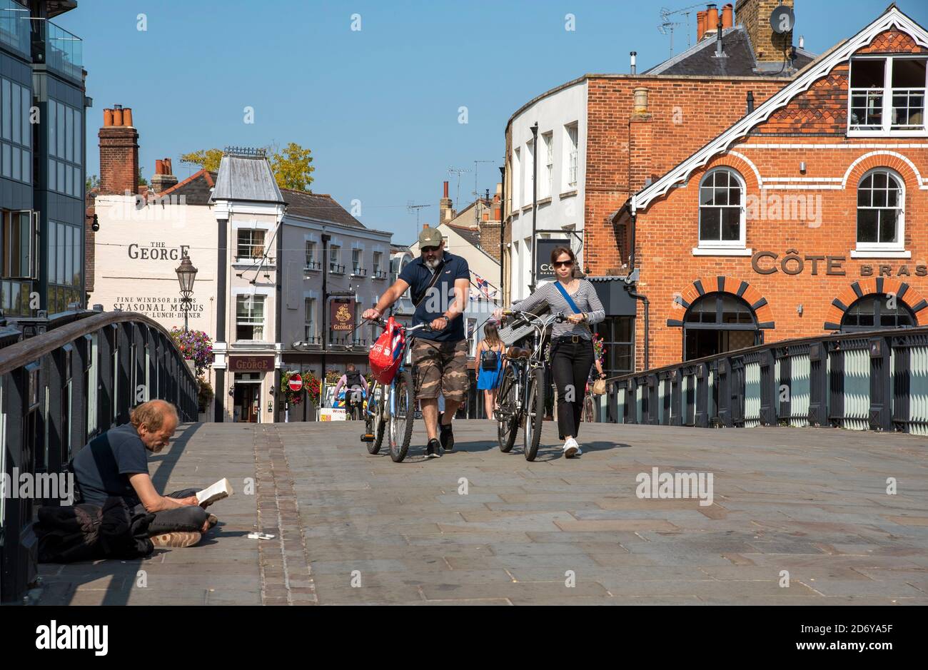 Eton, Buckinghamshire, Angleterre, Royaume-Uni. 2020. Les cyclistes font passer leurs bicyclettes devant un homme qui supplie le pont Windsor Eton qui traverse la Tamise Banque D'Images