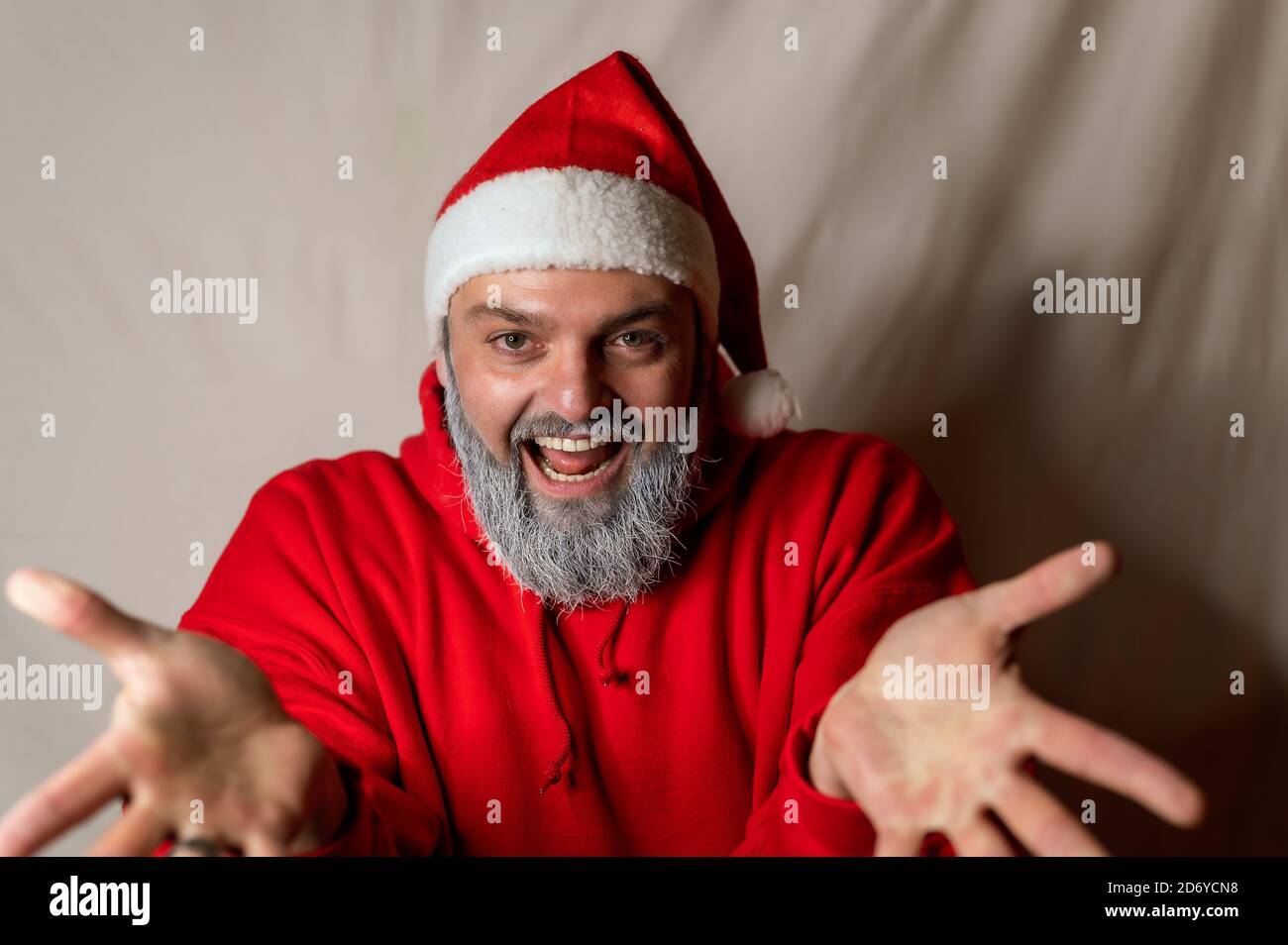 Le Père Noël se tient devant la caméra avec son les bras larges s'ouvrent et vous invite à un câlin avec un grand sourire Banque D'Images