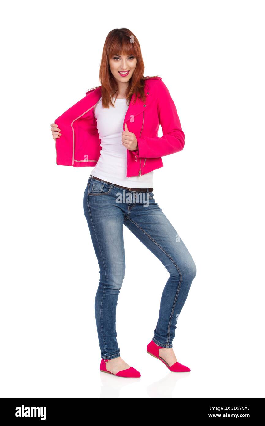 La jeune femme porte une veste rose non boutonnée ouverte en regardant l'appareil photo et en souriant. Prise de vue en studio sur toute la longueur isolée sur blanc. Banque D'Images