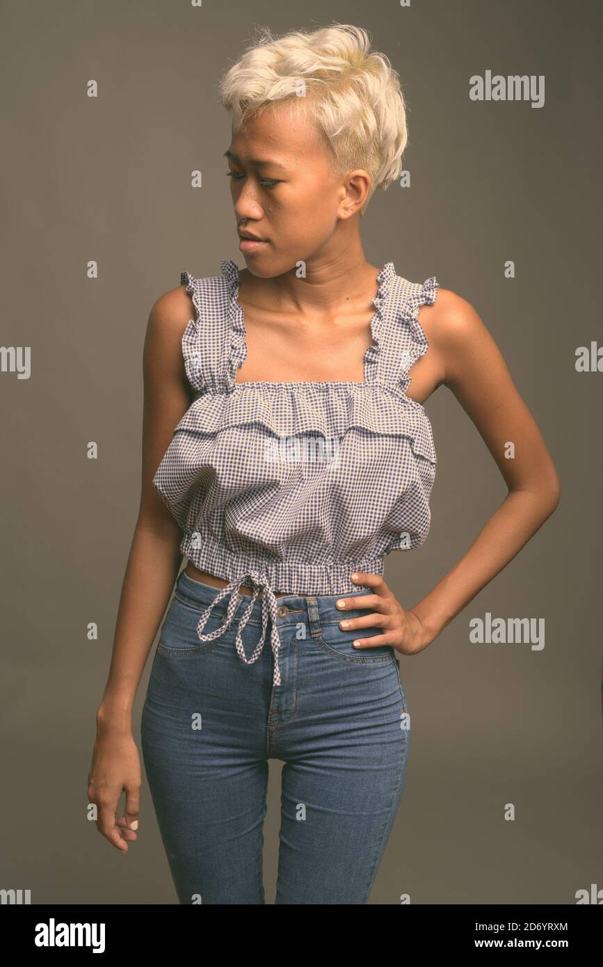 Jeune belle femme rebelle avec des cheveux courts sur fond gris Banque D'Images