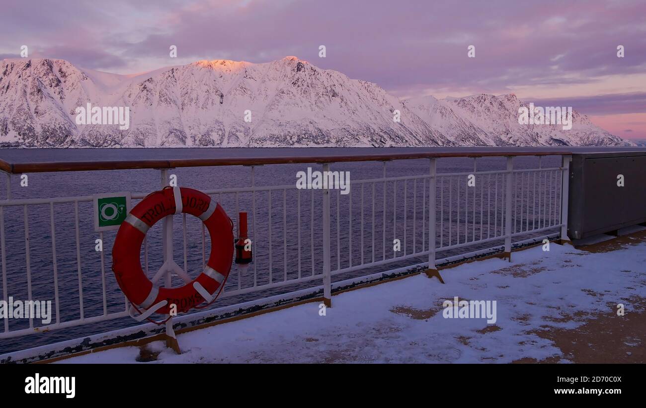 Sørøysundet, Norvège - 03/02/2019: Anneau de vie avec le nom du navire attaché à la rampe du pont supérieur du navire de croisière Hurtigruten avec ciel violet. Banque D'Images