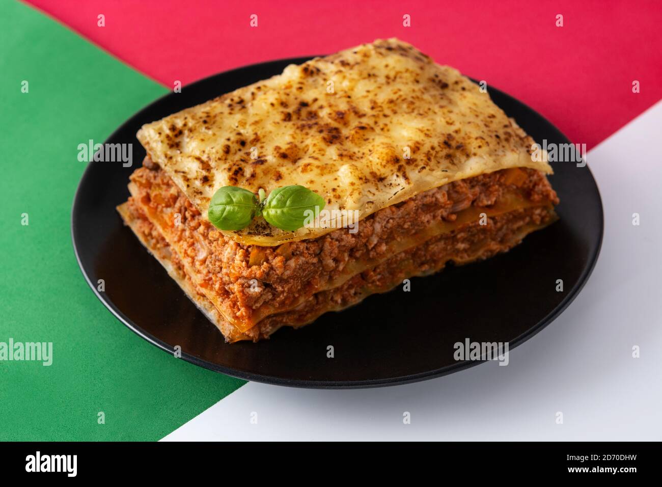 Morceau de lasagne à la viande sur fond rouge, blanc et vert Banque D'Images