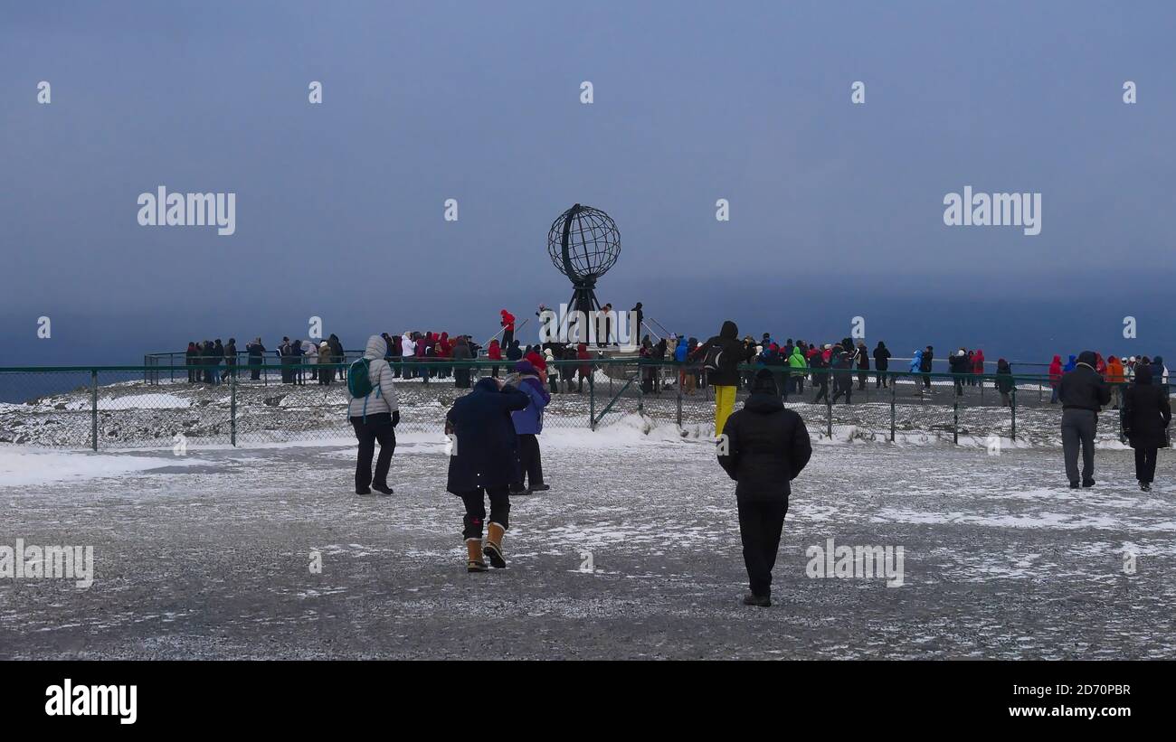 Nordkapp, Norvège - 02/28/2019: Les touristes d'un navire de croisière Hurtigruten lors d'une excursion d'une journée au Cap Nord rassemblant autour de la célèbre sculpture du globe en hiver. Banque D'Images