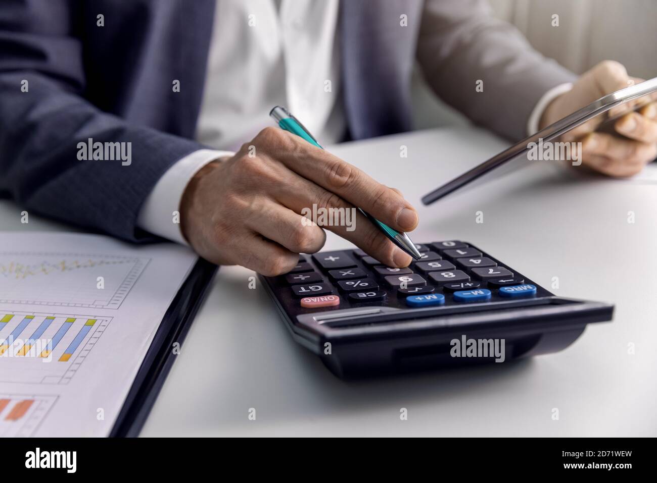 homme d'affaires analysant des graphiques et des graphiques financiers au bureau avec une calculatrice et une tablette numérique. rapports d'affaires, analyse de données Banque D'Images