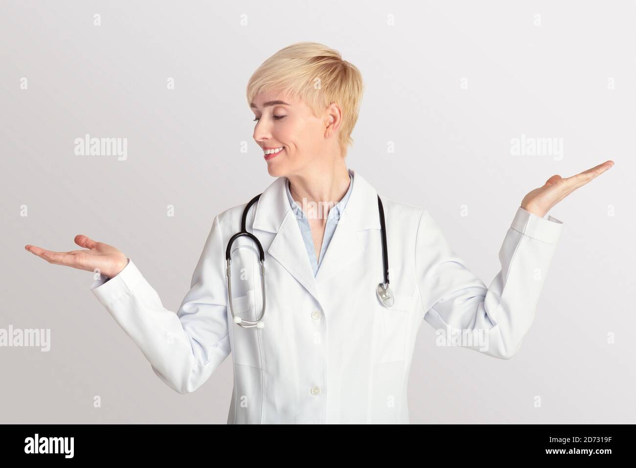 Femme adulte médecin en manteau blanc avec stéthoscope la lève mains de pesée Banque D'Images