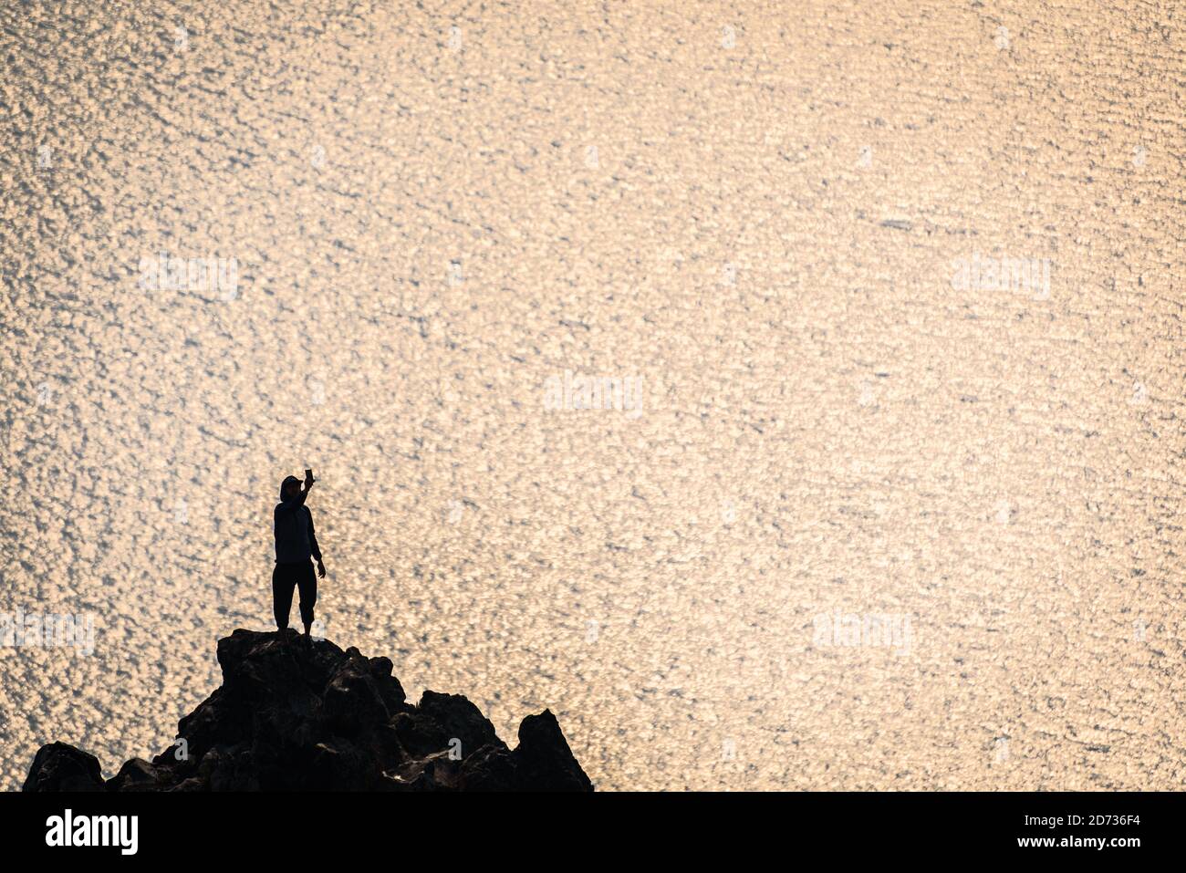 L'homme est silhoueté alors qu'il prend un selfie au-dessus du lac Crater, tandis que la fumée du feu de forêt obscurcit l'atmosphère au parc national de Crater Lake, Oregon, États-Unis. Banque D'Images
