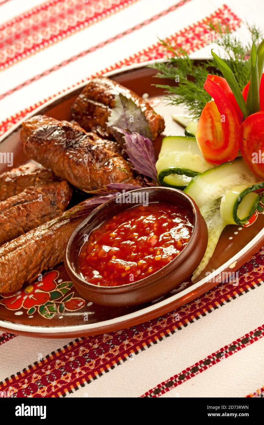 Viande grillée avec sauce chaude et légumes sur plaque de céramique Banque D'Images