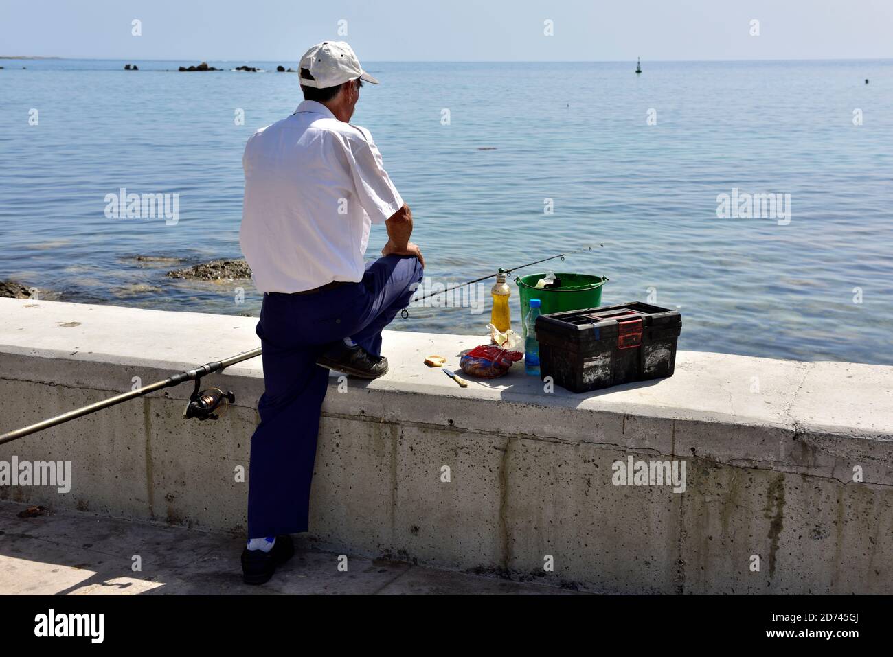 Pêcheur avec poteau et ligne sur le quai du port de Paphos, Chypre Banque D'Images