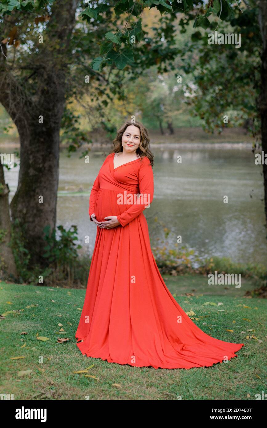 Femme vêtue d'une robe rouge pour les photos de maternité Banque D'Images