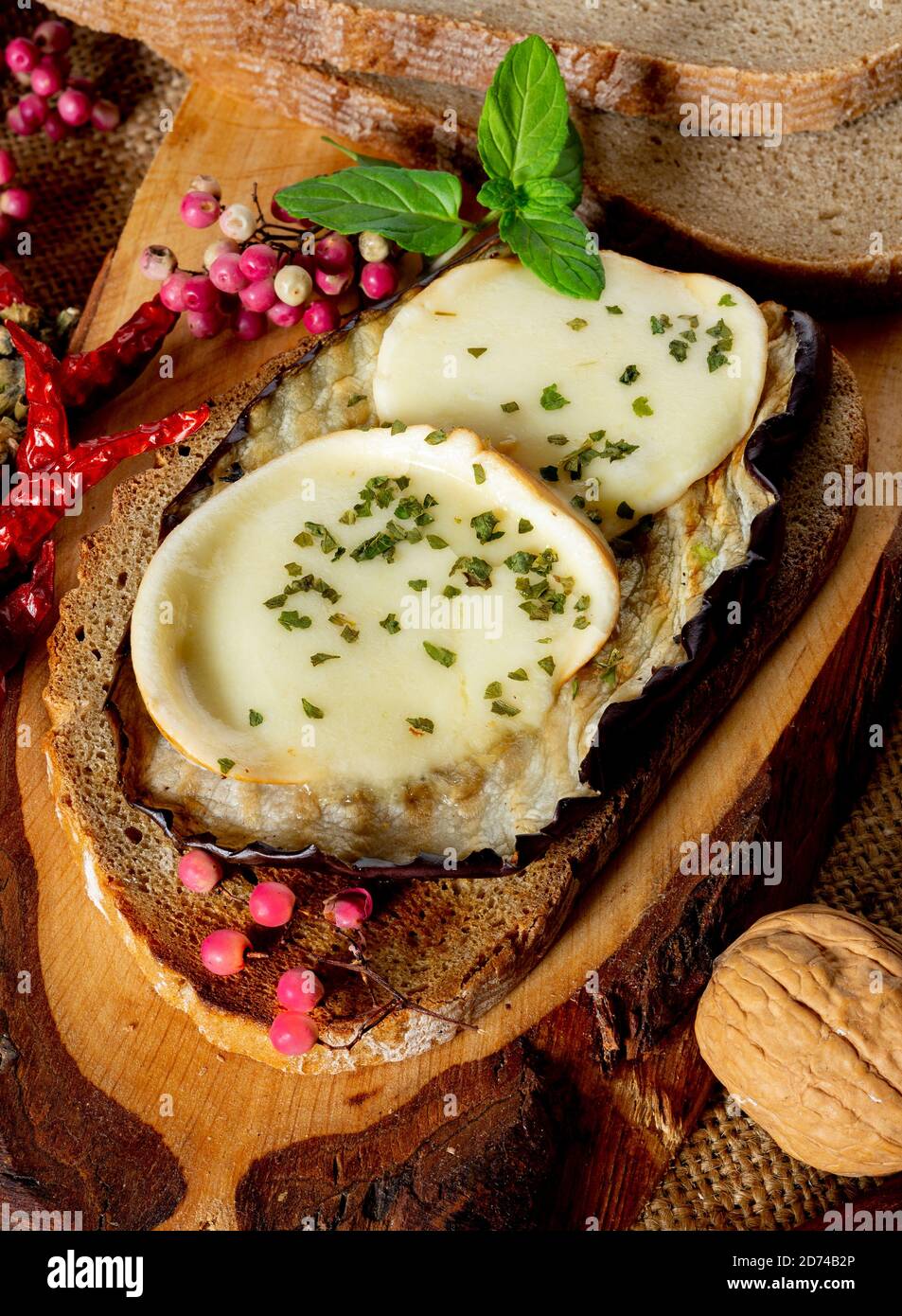 tranches d'aubergines cuites au four avec du fromage sur une tranche de pain avec de la farine complète, de l'huile d'olive, du persil et du poivre sauvage Banque D'Images