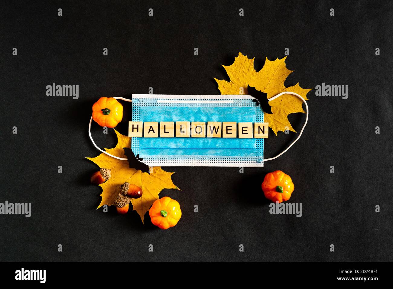 Citrouilles d'Halloween, masque médical protecteur et feuilles d'érable jaune sur fond noir, chauves-souris en papier noir. L'inscription HALLOWEEN le Banque D'Images