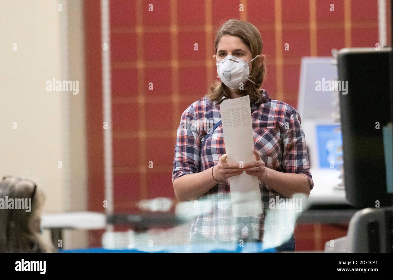 Austin, Texas le 20 octobre 2020 : un électeur masqué du comté de Travis passe en revue son bulletin de vote sur papier, généré par la machine électronique sur laquelle elle a voté à un bureau de vote par anticipation dans le nord d'Austin. Le bulletin de vote est exécuté par un scanner, puis stocké sous forme de copie papier de sauvegarde. Crédit : Bob Daemmrich/Alay Live News Banque D'Images