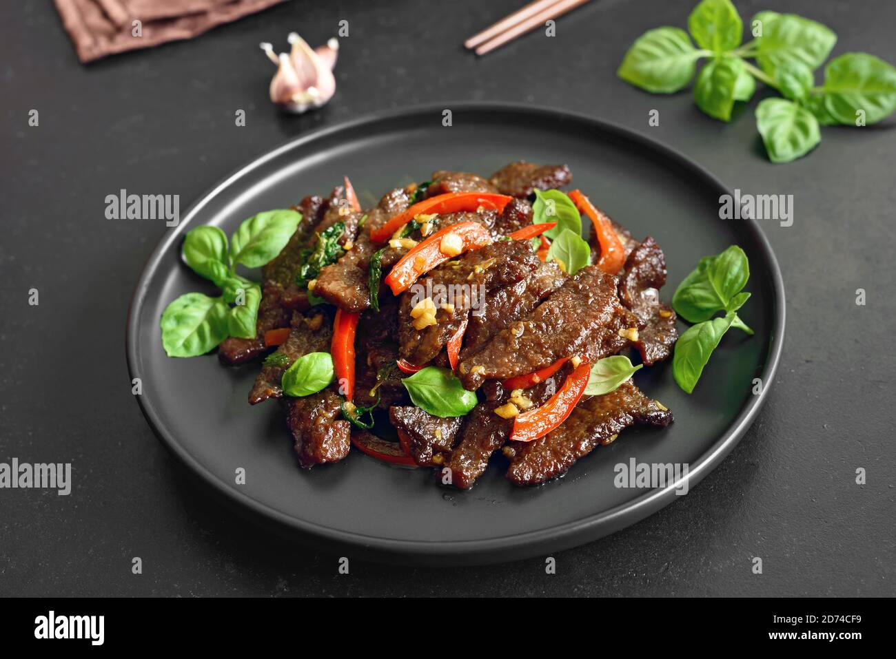 Sauté de bœuf thaïlandais avec poivre et basilic sur l'assiette un arrière-plan en pierre sombre Banque D'Images
