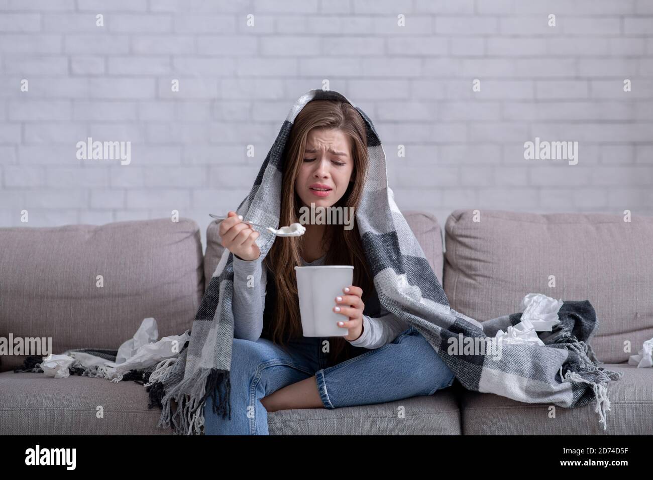 Concept de stress mangeant. Énervé femme mangeant de la crème glacée et pleurant sous le écossais chaud à la maison Banque D'Images