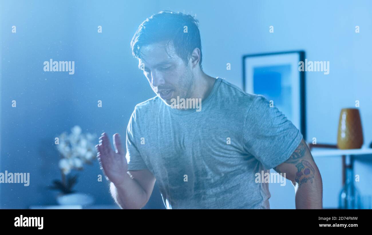 Gros plan d'un homme puissant et athlétique en T-shirt Concentré sur le jogging Energétique à la maison dans son spacieux et Appartement lumineux et minimaliste Banque D'Images