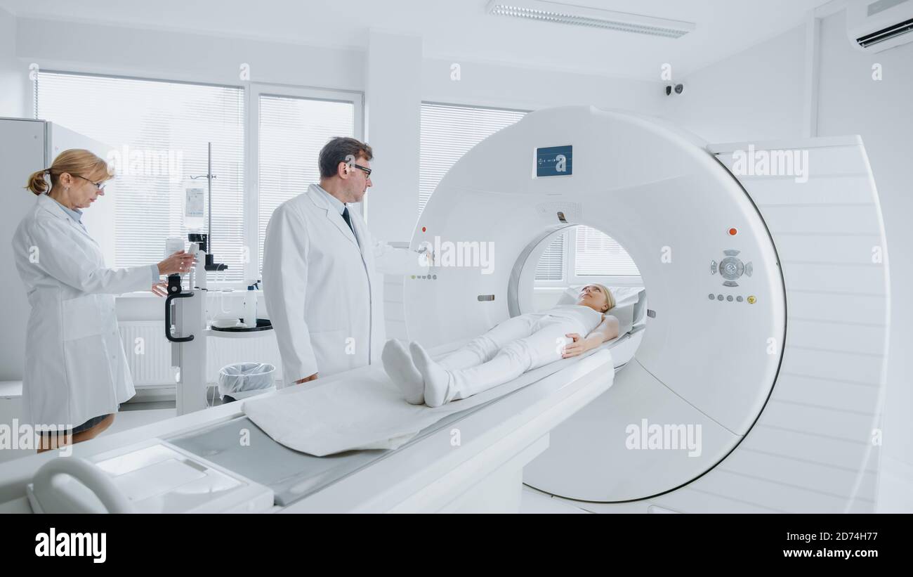 En laboratoire médical, les femmes radiologues et les hommes médecins contrôlent et contrôlent l'IRM ou l'acquisition CT avec une patiente en cours de procédure. Haute technologie moderne Banque D'Images