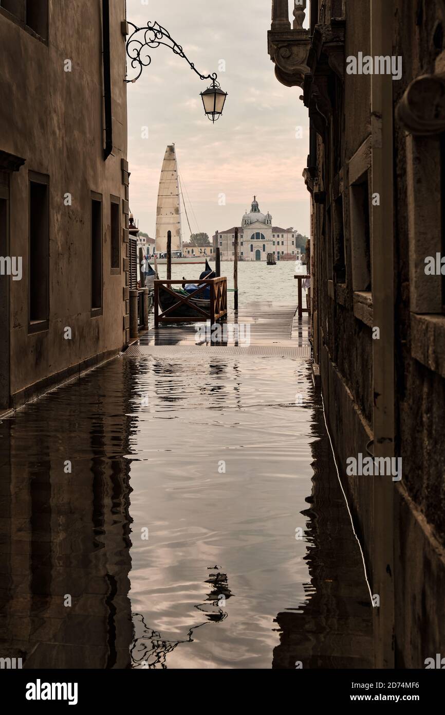 Vue sur Venise et un voilier depuis l'une de ses rues étroites inondées de marée haute, l'Italie Banque D'Images