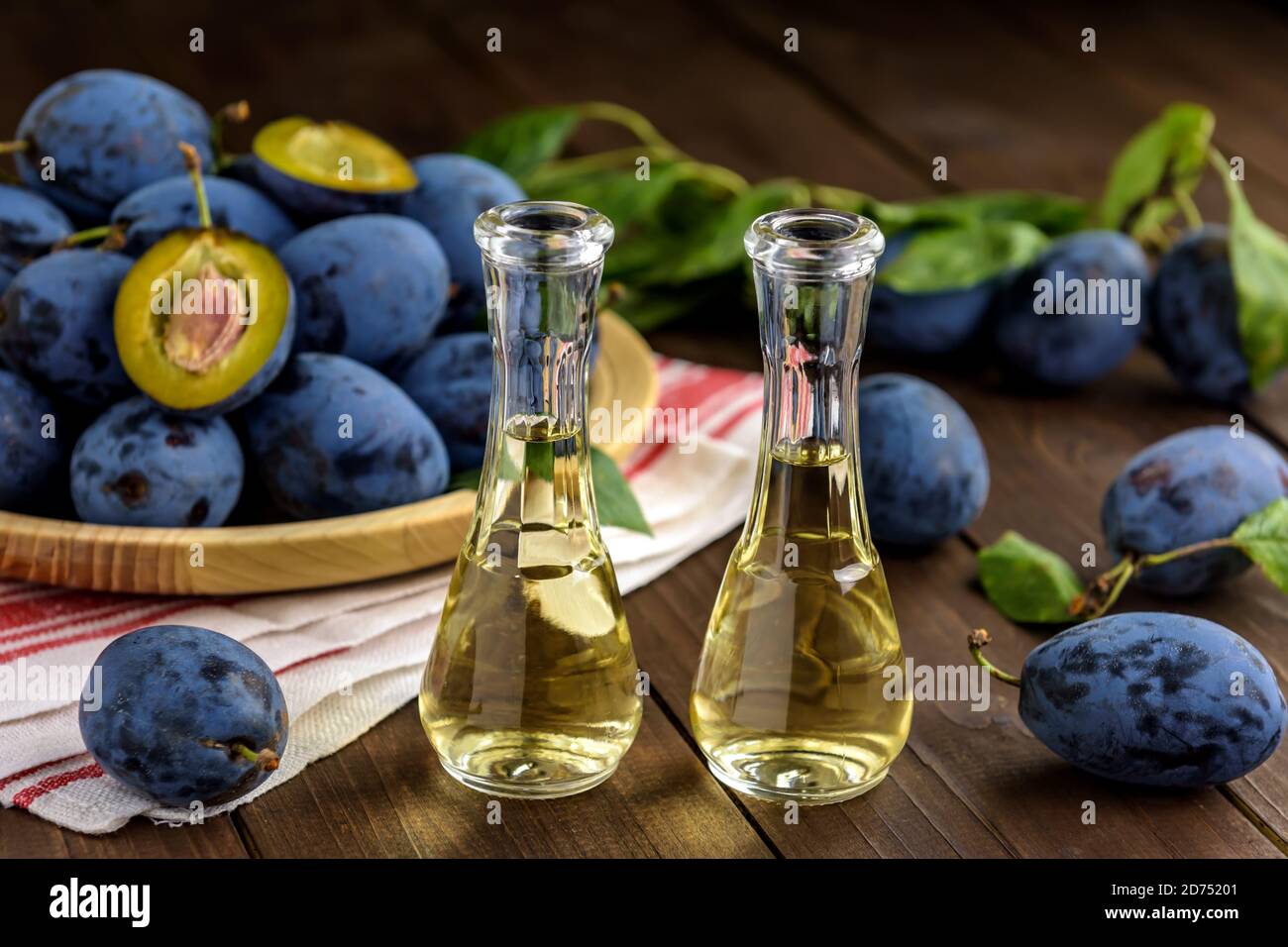 Brandy de prune ou schnaps dans de petites bouteilles de verre avec des prunes fraîches et savoureuses sur une table en bois. Mise au point sélective. Banque D'Images