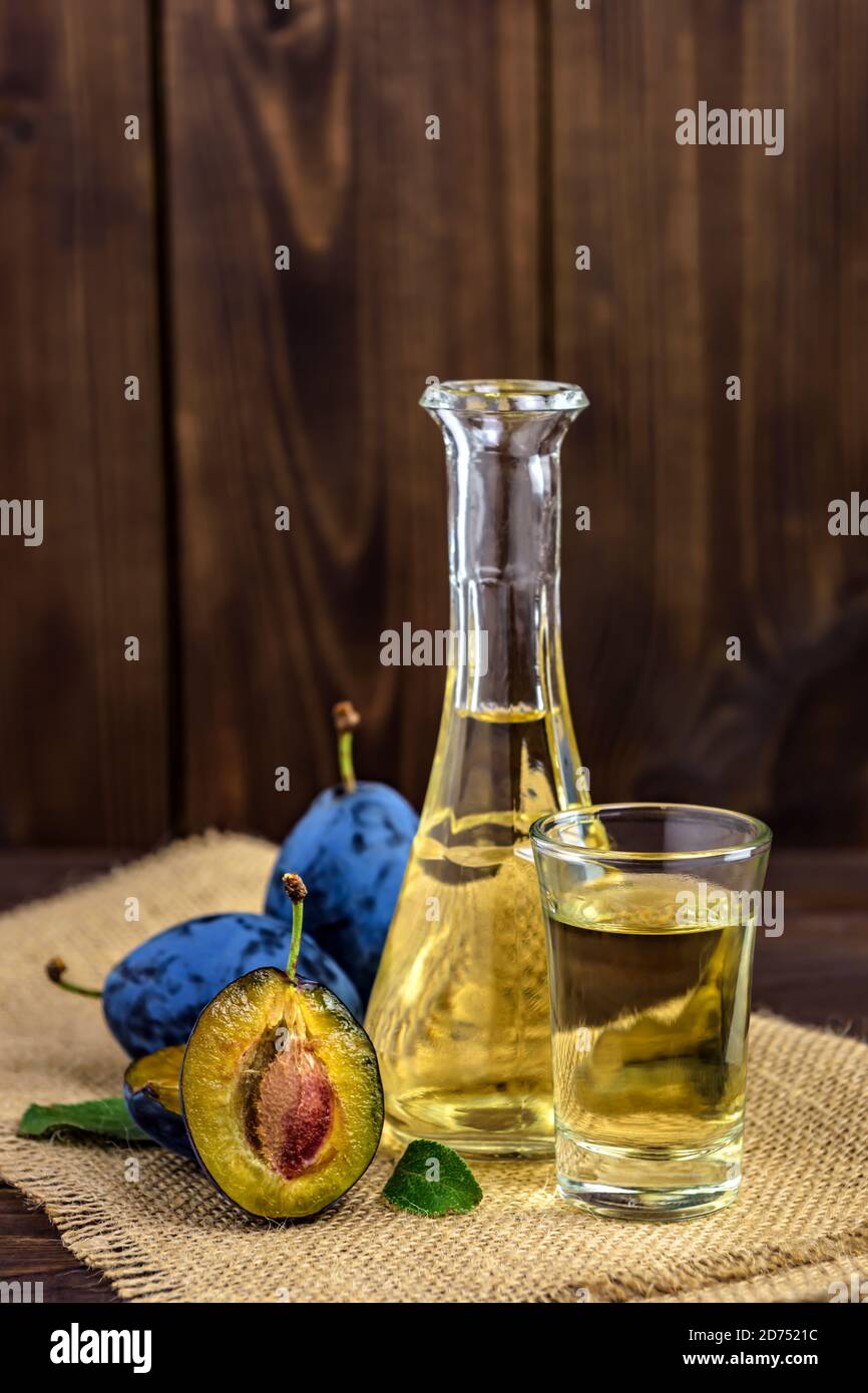 Brandy de prune ou schnaps dans des verres avec des prunes fraîches et savoureuses sur une table en bois. Mise au point sélective. Banque D'Images
