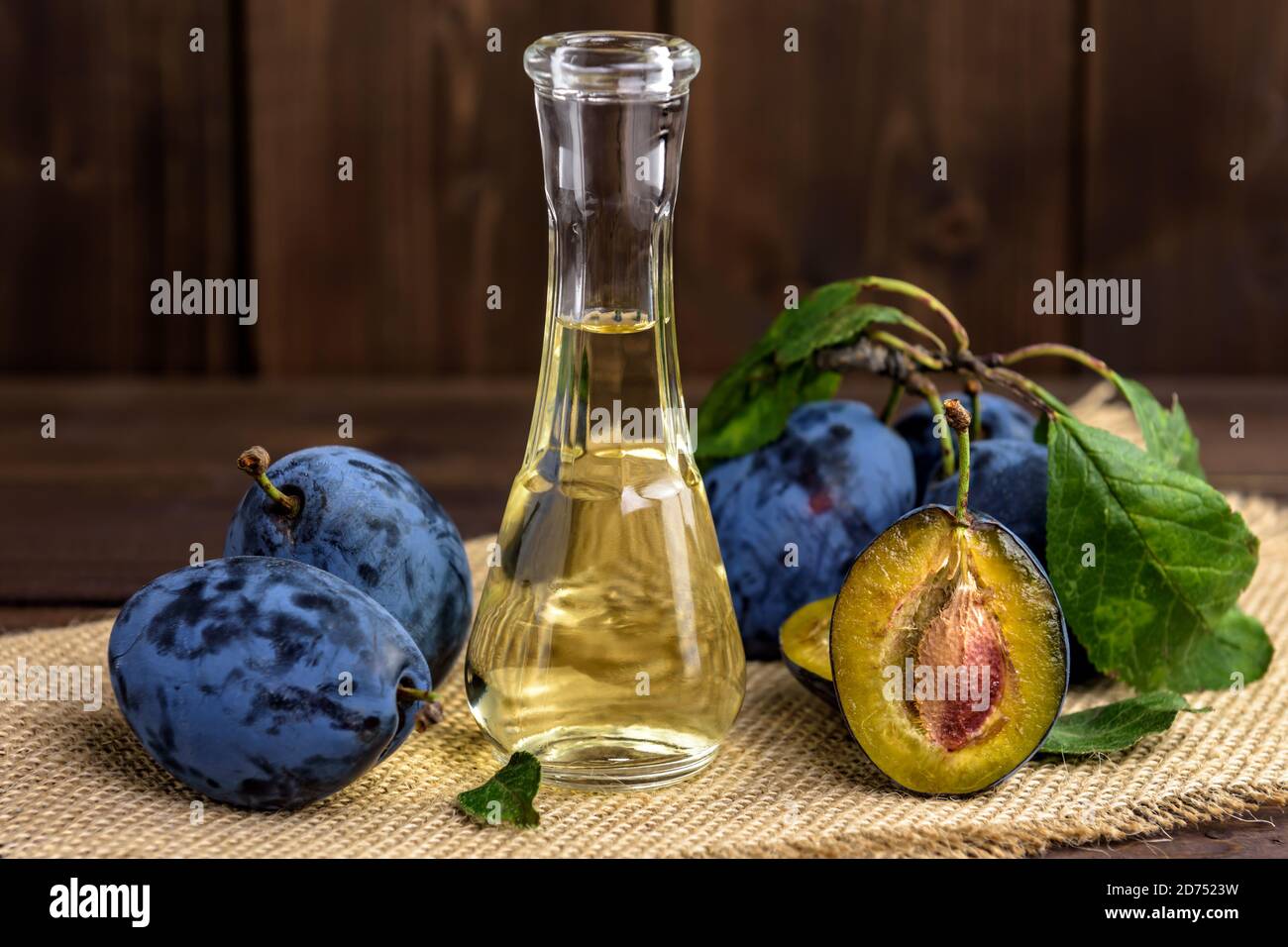 Brandy de prune ou schnaps dans une petite bouteille en verre avec prunes fraîches et savoureuses sur une table en bois. Mise au point sélective. Banque D'Images