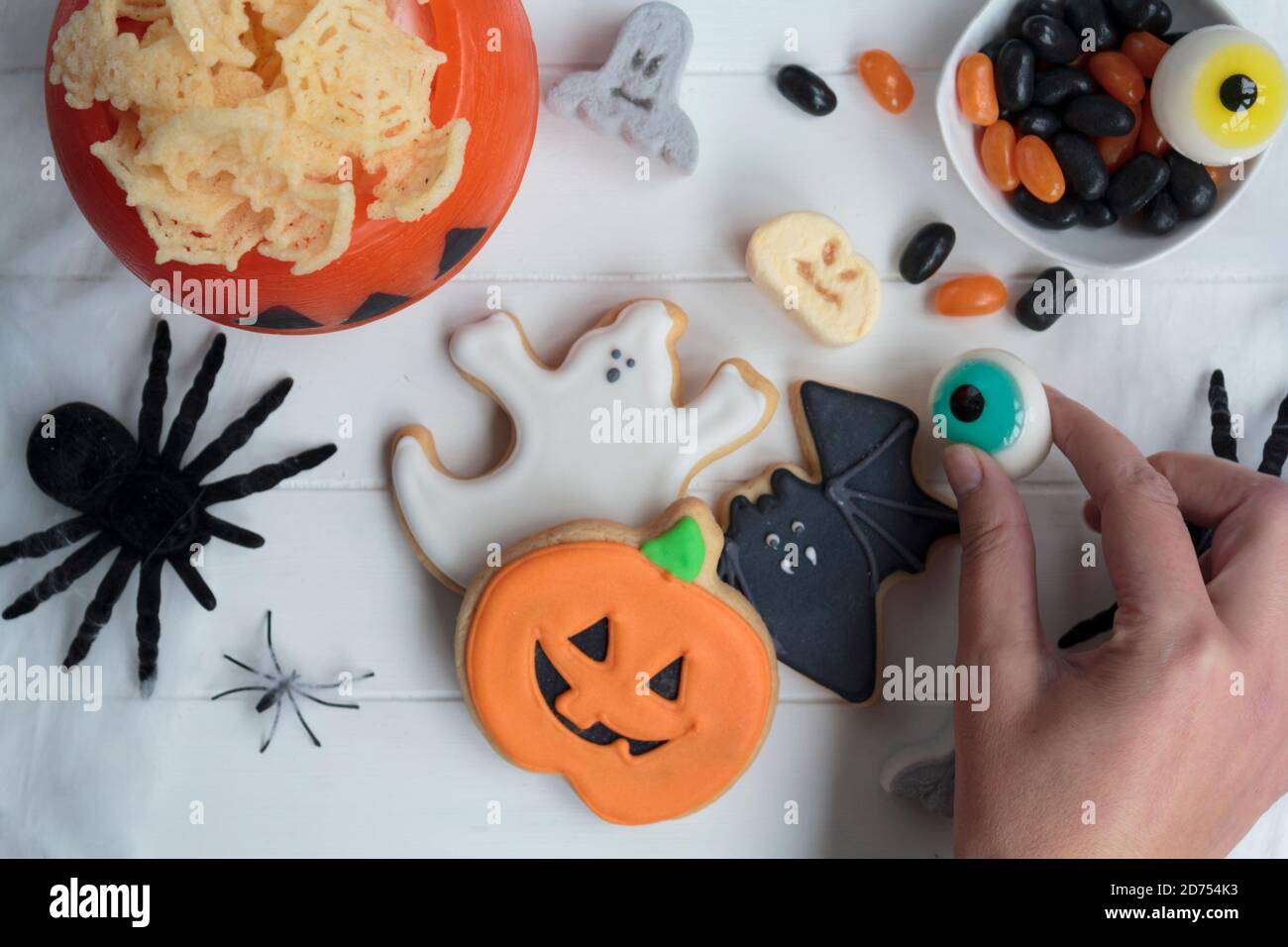 Main de femme tenant un oeil d'halloween, sur la table avec d'autres gâteries d'halloween Banque D'Images